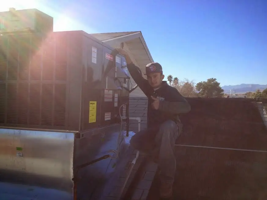 HVAC technician performing Air Duct Cleaning on a rooftop unit in Riverside